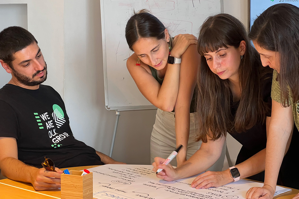 Three women and a man working together, writting on a sheet of paper for a presentation.